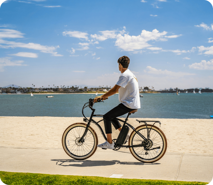 young man riding bike along beach in california