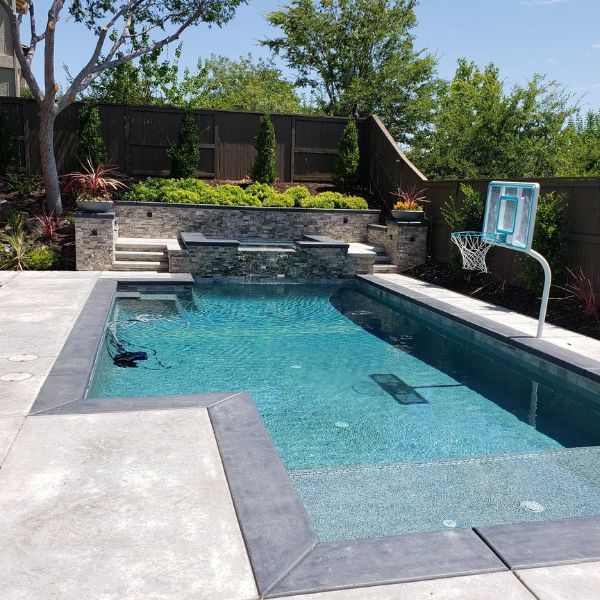 A backyard pool with a basketball hoop