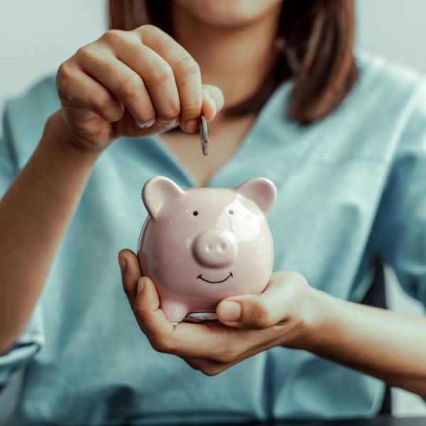 Women placing a coin into a piggy bank