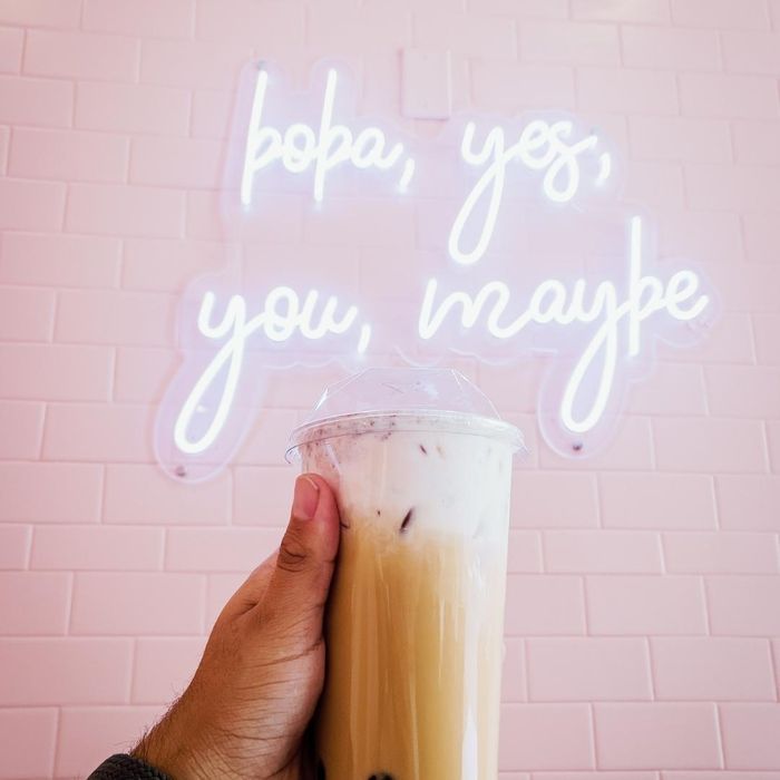 boba drink in front of neon sign: boba yes, you, maybe