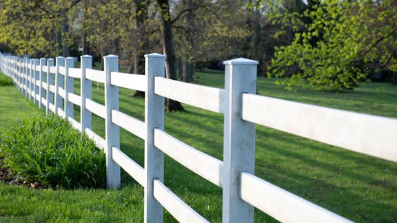 White fence lining a green lawn.