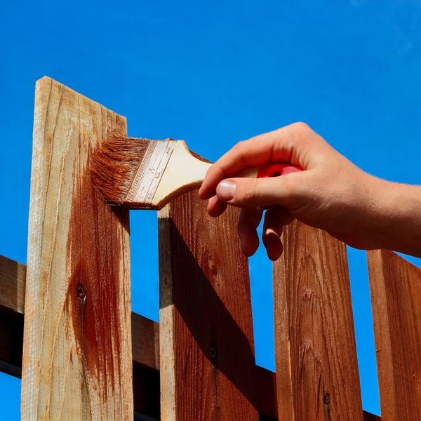 Person applying wood stain to a fence