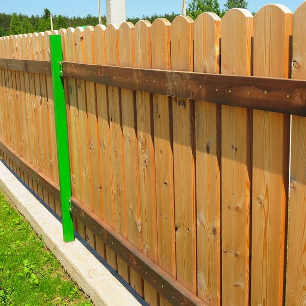 a round top wooden fence with green posts