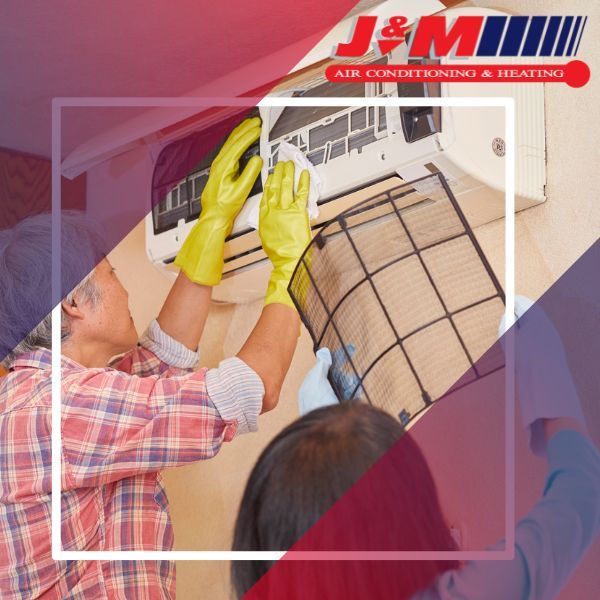 Man and woman replacing air filter in ac unit