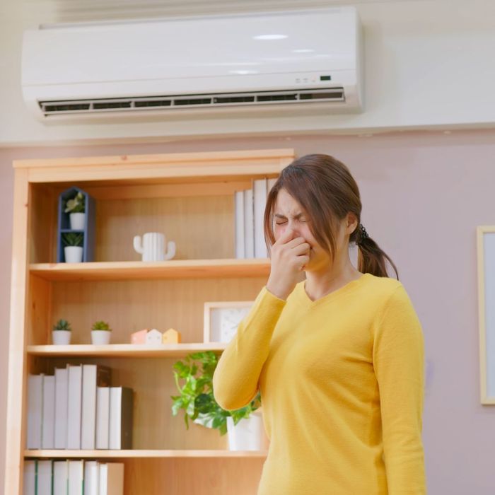 woman plugging her nose around her ac unit