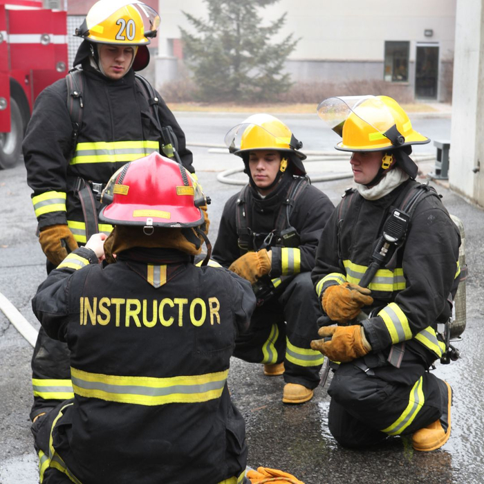 An instructor talking with three firefighters in training