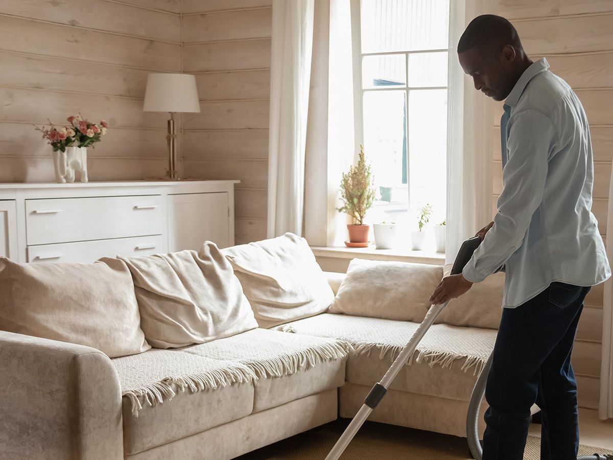 An image of a man vacuuming in a modern living room.