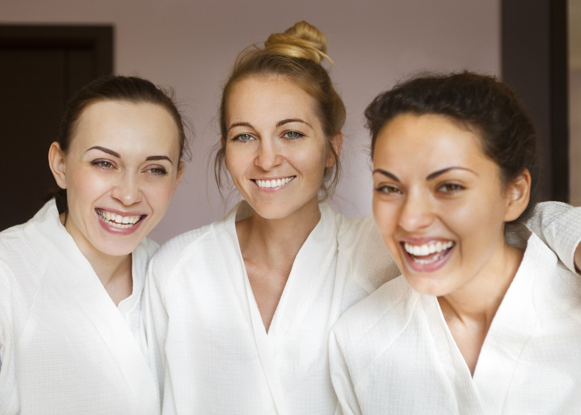 Group of friends in white robes at a med spa for facials and other treatment.