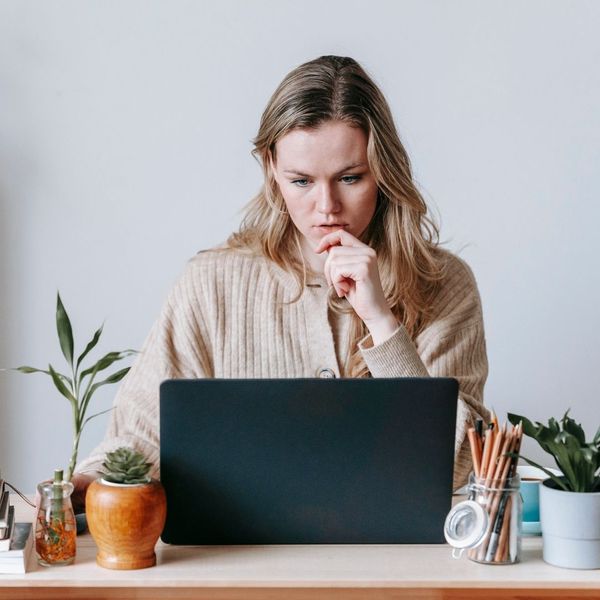 woman thinking, researching on laptop