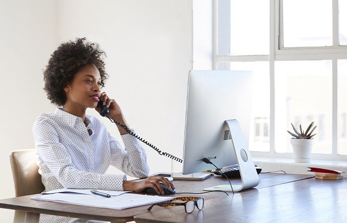 a business woman on a phone call in front of a computer and paperwork