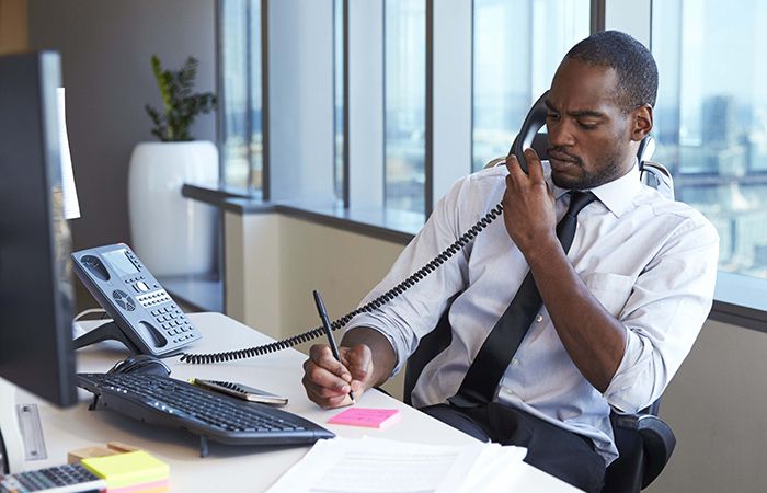 a man on the phone taking notes at his desk