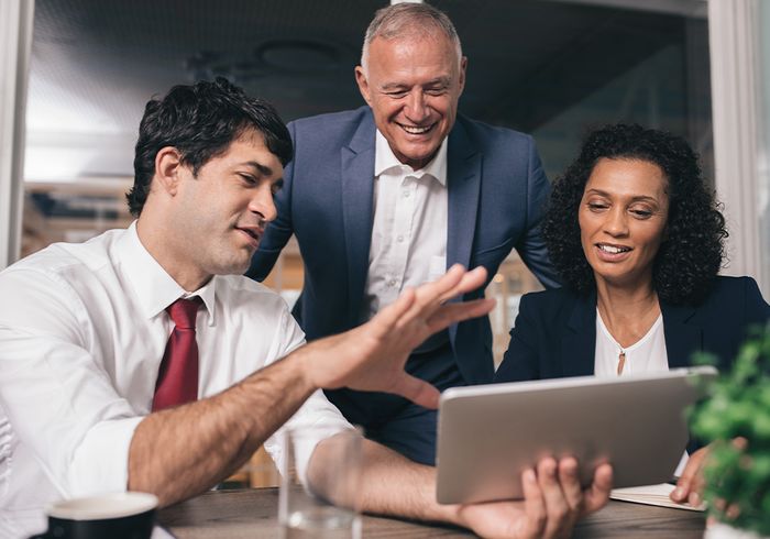 business people talking together and looking at a tablet