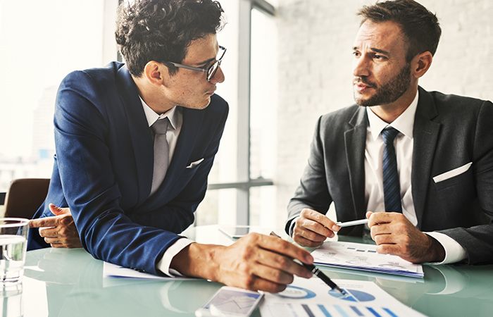 business men discussing paperwork with charts on them