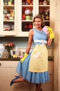 a woman in vintage fifties clothing posing with a sponge in the kitchen