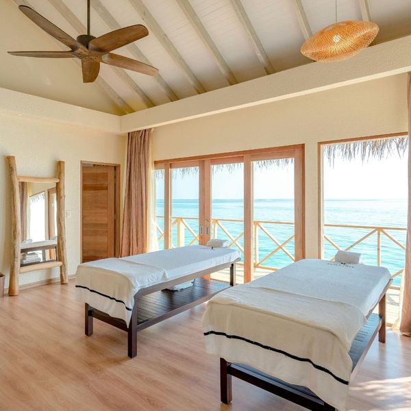 The interior of a spacious, sunlit spa room with two massage tables, a vaulted ceiling, and large glass doors that open to a balcony. It suggests a relaxing and luxurious travel experience. The interior of a spacious, sunlit spa room with two massage tables, a vaulted ceiling, and large glass doors that open to a balcony. It suggests a relaxing and luxurious travel experience.