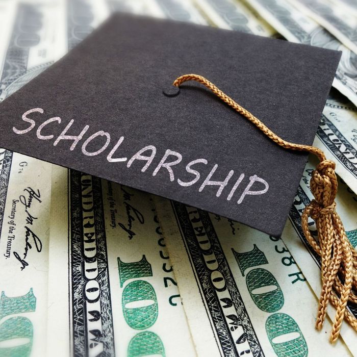 Graduation cap with 'Scholarship' written on it over lines of $100 bills