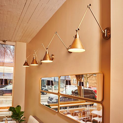 Gold sconces in a row above mirrors in a restaurant