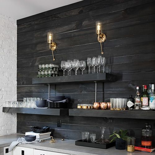 Two gold sconces on a dark wood wall above shelves