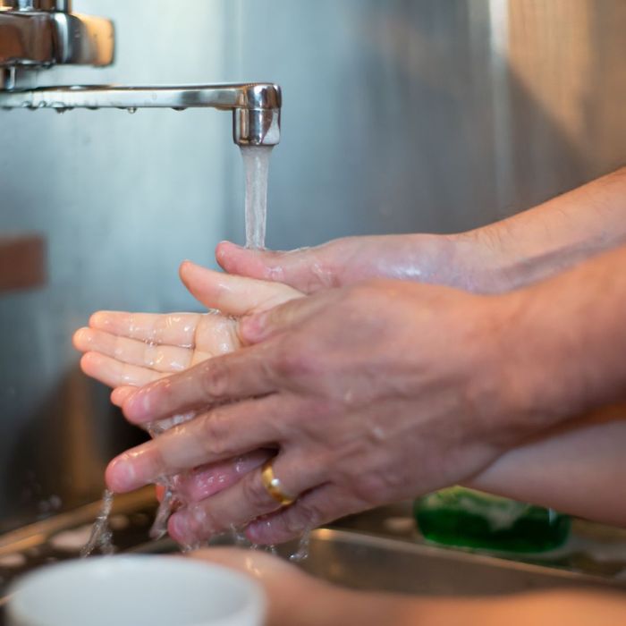 adult helping child wash hands