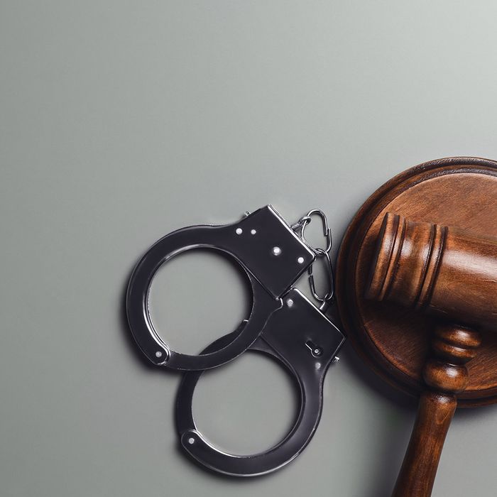 Judge's gavel and handcuffs on grey background