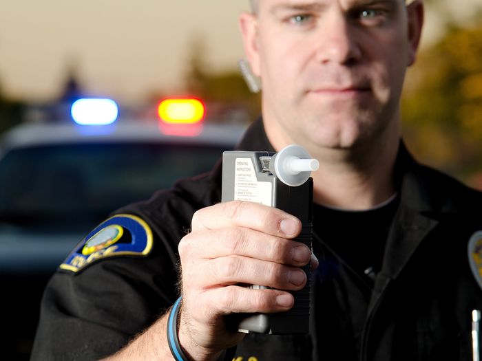 photo of police man holding up breathalyzer 