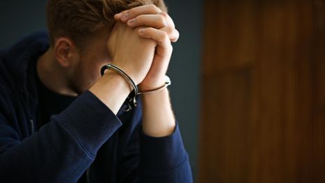 Handcuffed man with his head in his hands