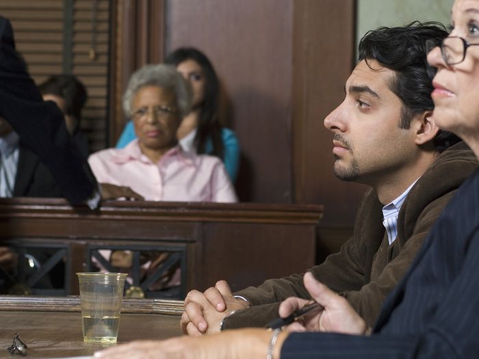 Defense lawyer sitting with client during prosecution in courthouse