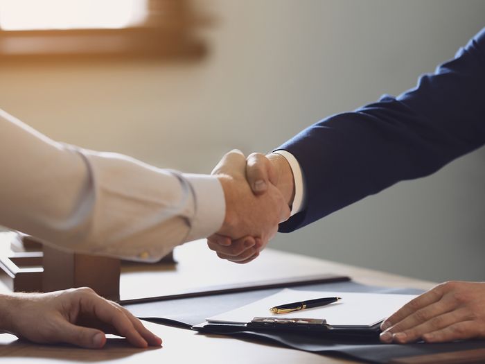 Male lawyer shaking hands with client in office, closeup 