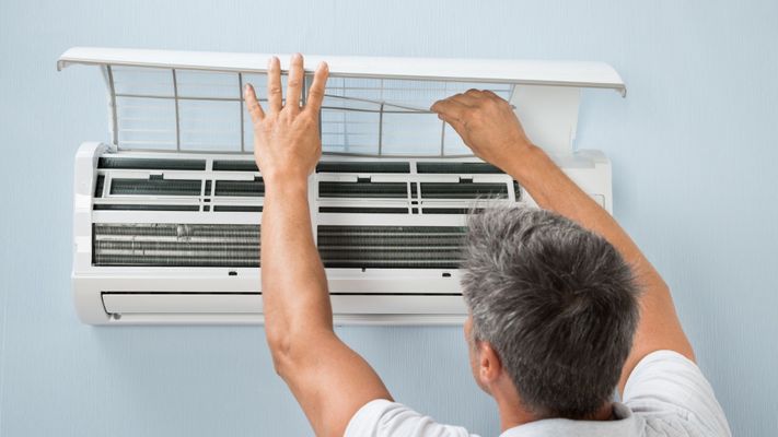 Man checking the filter and maintenance of a mini-split indoor unit.