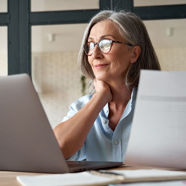 Woman studying documents at a laptop, representing smart financial decision making. Woman studying documents at a laptop, representing smart financial decision making.