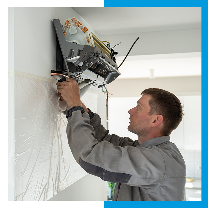 Man installing a mini split AC unit in a home