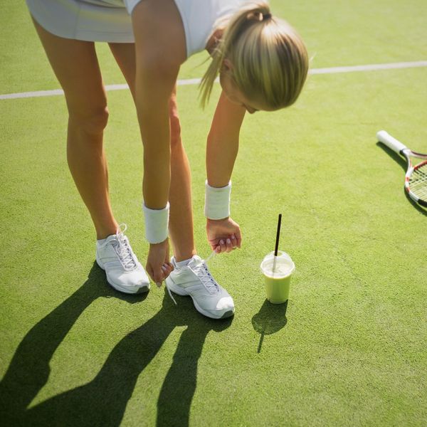 girl tying her tennis court shoe