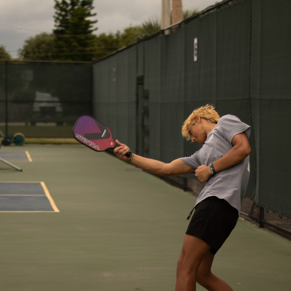 A male player with his pickleball paddle in a celebratory pose on the court. A male player with his pickleball paddle in a celebratory pose on the court.