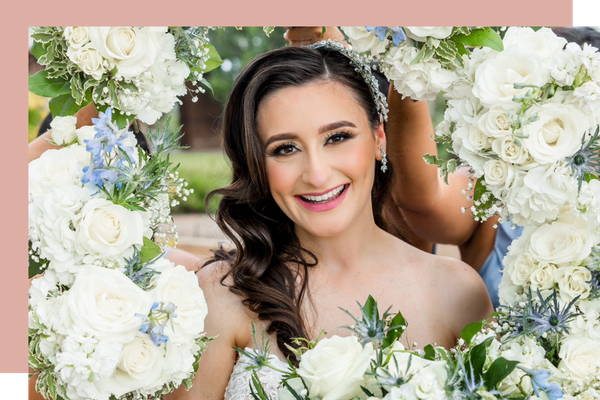A bride smiling with a flower arrangement framing her