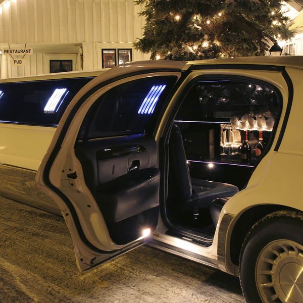 a limo with the doors open in front of a lit christmas tree