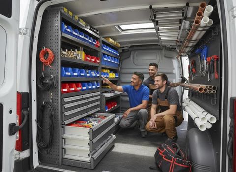 A team of three service technicians examines the custom storage solutions, including bins, drawers, and tool racks, inside a white work van. Service Professionals in Organized Work Van