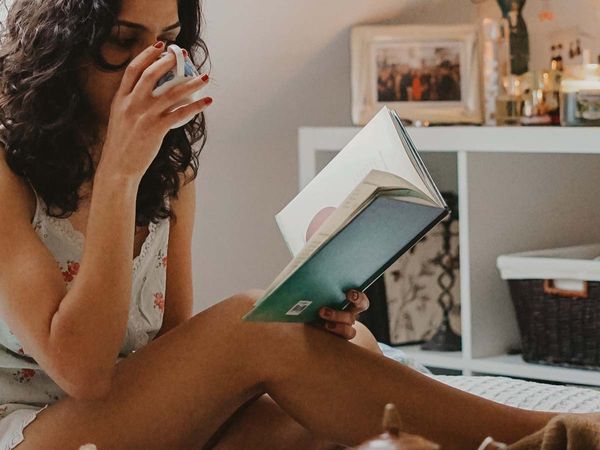 Picture of woman reading in bed and drinking coffee