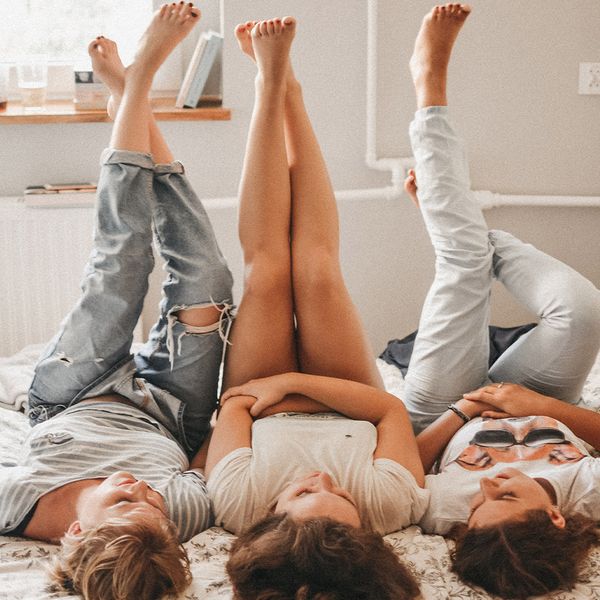 Young women laying on the bed together with feet in the air.