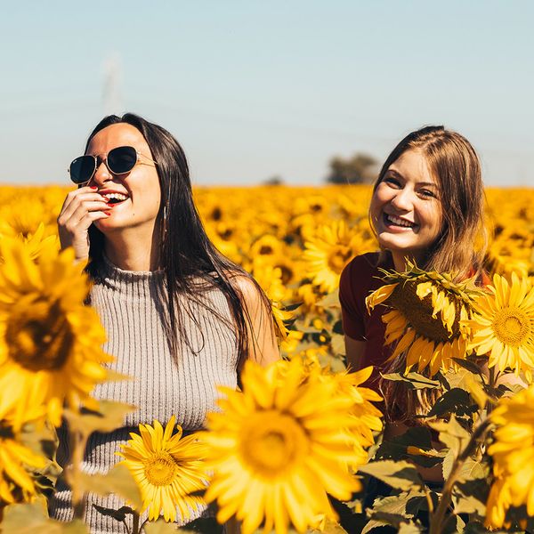 Young women laughing in sunflower field.