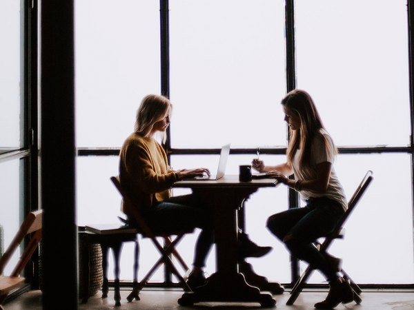 A surrogate and a potential mother sitting down and discussing their parenting prospects.