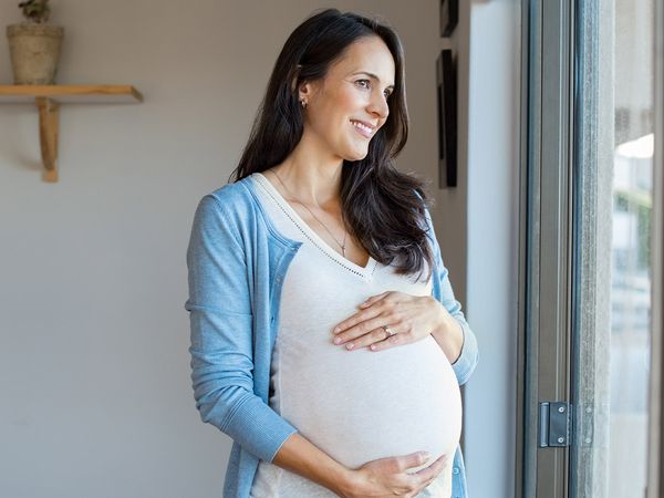 Glowing pregnant woman looking out window