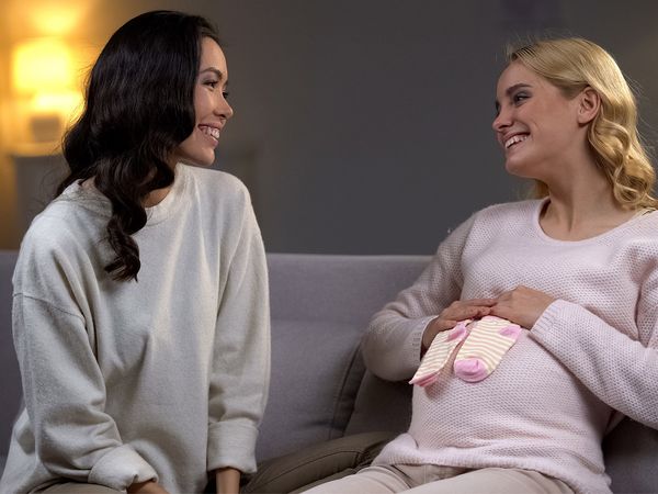 Pregnant woman sitting on couch with Egg Donor.