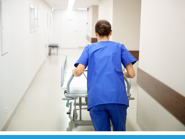 nurse pushing patient bed down hallway