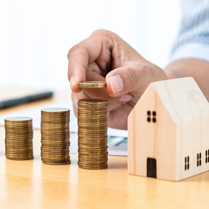 increasing stacks of coins next to a model house