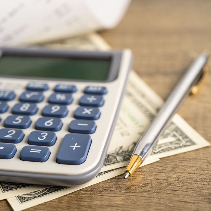 a pen, calculator, and dollar bills on a table