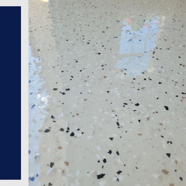Close-up of a smooth, high-shine cream epoxy floor with black, white, and tan decorative chips.