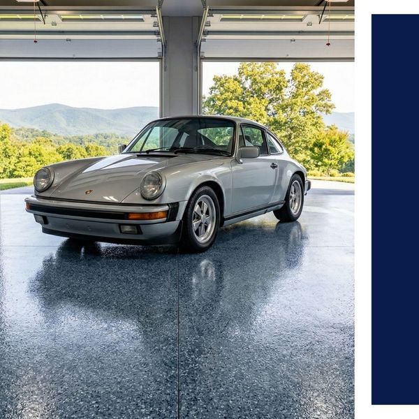 Luxury garage interior featuring a silver vintage sports car on a blue flake epoxy floor with mountain views.