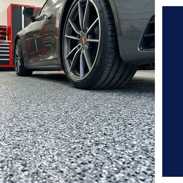 Sports car wheel on grey flake epoxy garage floor.