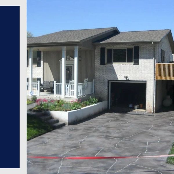 Residential driveway featuring a custom slate-grey stained concrete finish with flagstone patterns.