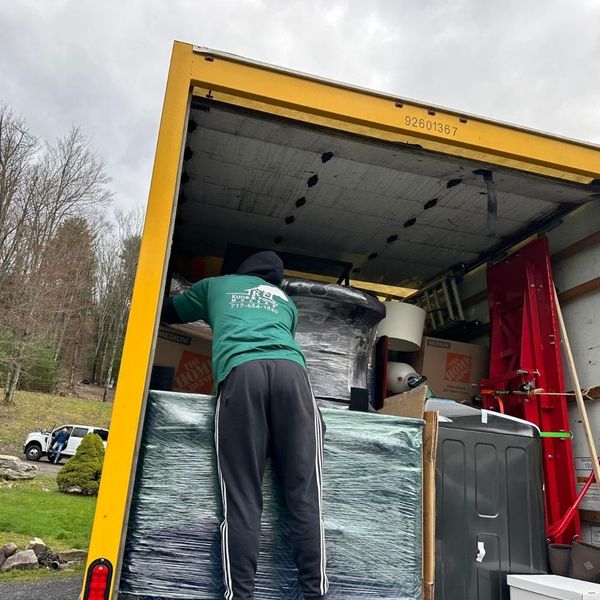 Professional mover loading a plastic-wrapped couch into a moving truck. Professional mover loading a plastic-wrapped couch into a moving truck.
